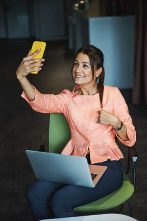 Beautiful elegant woman branding consultant in formal clothes talking on video call in working spaceの写真素材