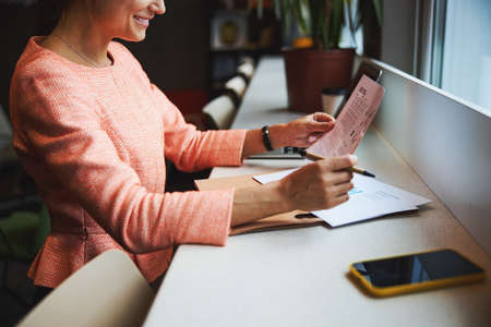 Young cheerful Caucasian woman in formal stylish jacket working with agreement in the co-working...