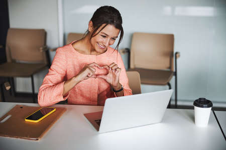 Smiling pretty online teacher talking with participants on video call while using laptopの写真素材