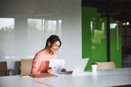 Brunette charming Caucasian female business analyst holding report in handsの写真素材