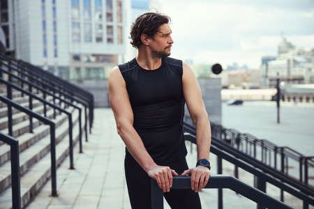 Portrait of thoughtful athlete leaning on banisters
