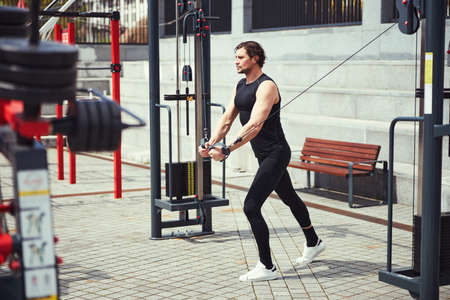 Strong male person using modern equipment for training