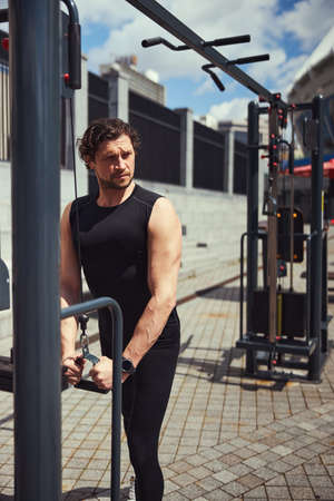 Serious brunette man doing exercises on muscles