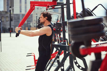Serious man leaning on support while doing exercise