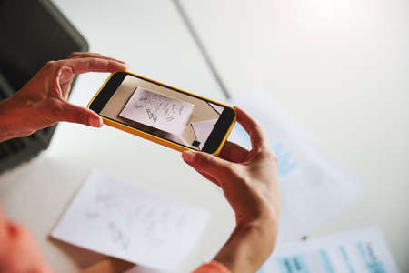 Unrecognized woman personal assistant using cell phone while working in the luxury officeの写真素材
