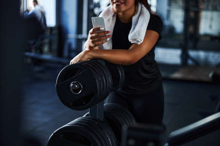 Smiling woman resting with smartphone after workoutの写真素材