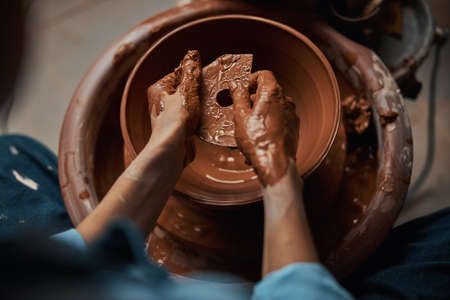 Unrecognized professional ceramist working with fresh wet clay in art studioの写真素材