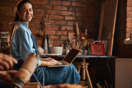 Beautiful elegant young Caucasian sculptor sitting on the chair while looking away in art studio