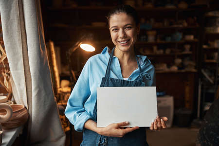 Beautiful elegant craft woman posing and looking at the photo camera in art modern studioの写真素材