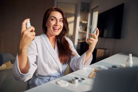 Positive delighted brunette woman using natural cosmetics