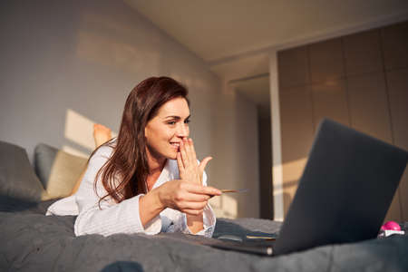 Positive delighted young beauty having online conversation