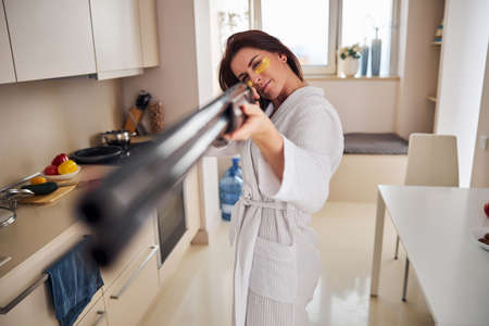 Active housewife looking through the sight of gunの写真素材