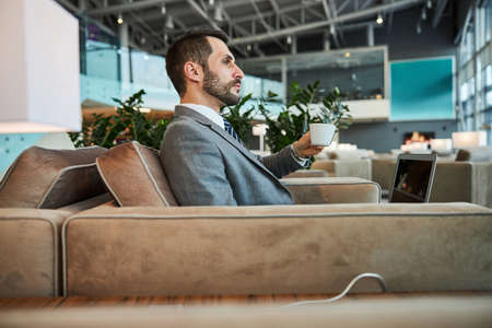 Thoughtful glance of a calm businessman in airportの写真素材
