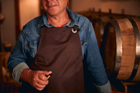 Unrecognized male sommelier in apron and denim shirtの写真素材