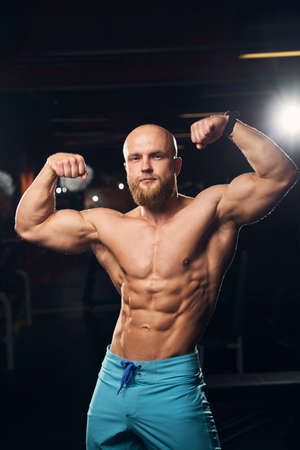 Handsome young athlete wearing shorts and flexing his musclesの写真素材