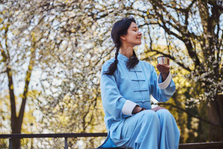 Satisfied martial artist having a break with tea in nature