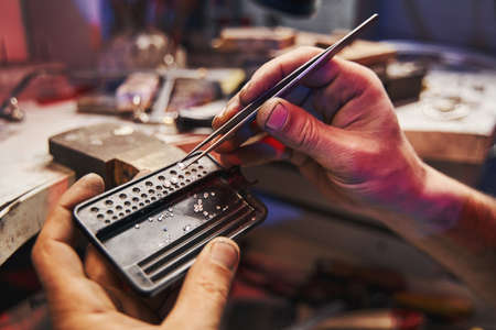 Person is checking diamond held in tweezers
