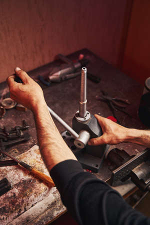 Jeweler increasing the size of ring with mandrel
