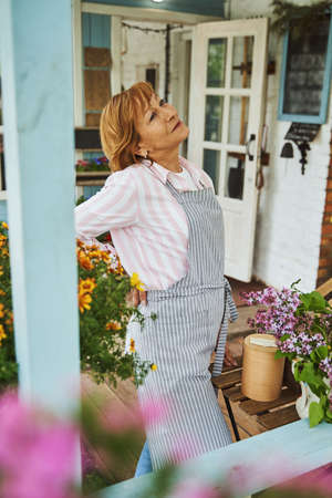 Happy elderly woman on terrace of flower shopの写真素材