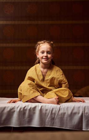 Happy kid in lotus position looking with charming smileの写真素材