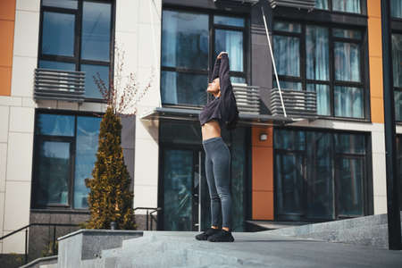Serious sportswoman performing the standing torso stretch outside