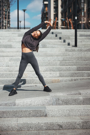 Pleased athletic female doing a lateral flexion outdoors