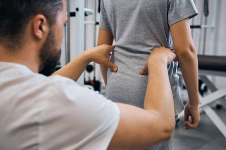 Chiropractor man checks incorrect posture of girl closeup back view. Physiotherapist manの写真素材