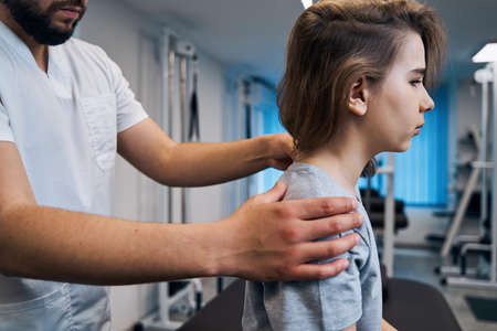 Professional manual therapist treats little girls neck on massage bed closeup. Osteopath-masseurの写真素材