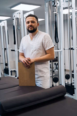 Portrait of bearded caucasian doctor with clipboard in hands.Serious confident professional masseurの写真素材