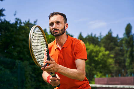 Serious focused young man playing tennis outdoorsの写真素材