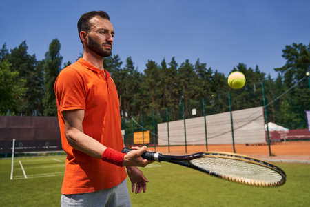 Concentrated mustached bearded athlete bouncing the ball on the racquetの写真素材