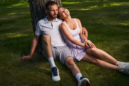Loving attractive couple seated by a treeの写真素材