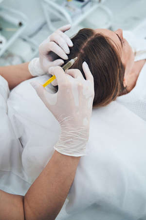 Close up of cosmetologist doing hair procedureの写真素材