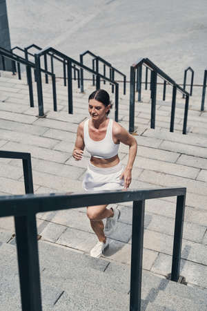Running sportswoman passing flight of stairs outsideの写真素材