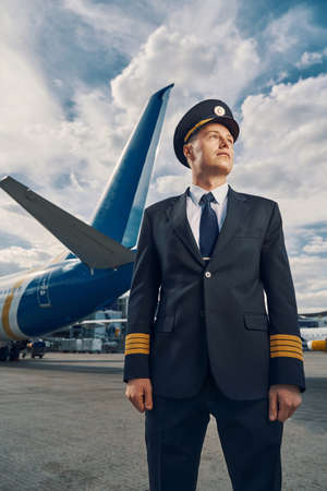 Attractive professional aviator dressed in uniform looking awayの写真素材