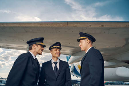 Three aviators having a conversation by a landed jetliner