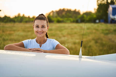 Young amazing woman leaning on the private plane