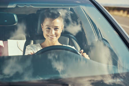 Happy woman driving in a car and smiling