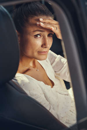 Lady in car looking at camera holding palm over eyesの写真素材