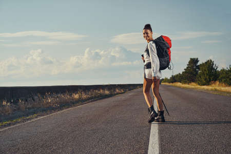 Female backpacker turning around while travelling through road