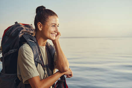 Satisfied female tourist is admiring lake surfaceの写真素材