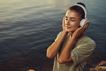 Female getting lost in music at lakesideの写真素材