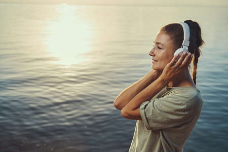 Tourist relaxing with music in her headphones at lakeshoreの写真素材
