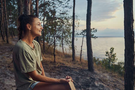 Female enjoying a lake view while holding a logの写真素材
