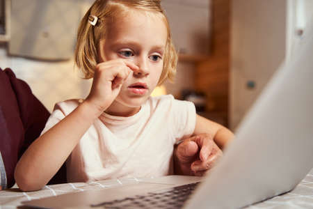 Girl scratching her nose while working at laptopの写真素材