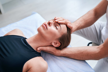 Unrecognized male physiotherapist working with attractive woman in medical officeの写真素材