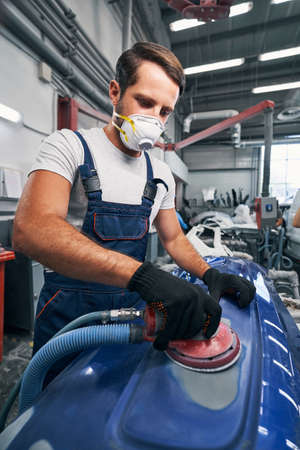 Auto mechanic in respirator using sander on car surfaceの写真素材