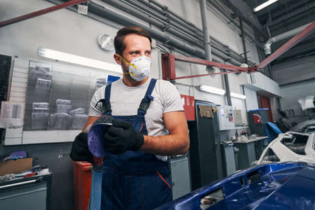 Auto mechanic taking off sandpaper disk from sanderの写真素材