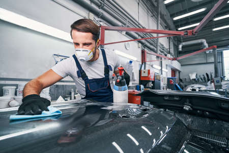 Car cleaning performed by auto mechanic in workshop