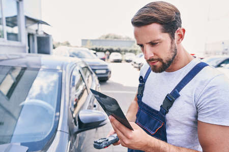 Professional repairman checking shades cards for car painting outdoorsの写真素材